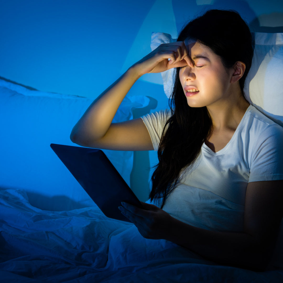 tired woman in bed still using computer