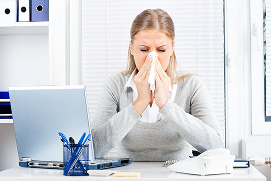 woman sneezing at desk