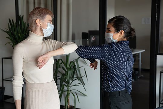 coworkers in masks bump elbows